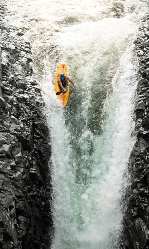 man in kayak going over waterfall